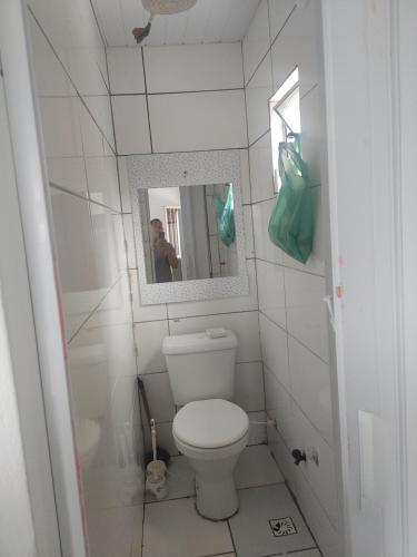 W łazience znajduje się biała toaleta i lustro. w obiekcie Quitinete w mieście Rio de Janeiro