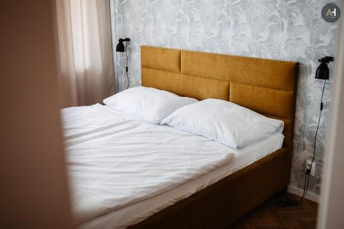 uma cama com lençóis brancos e almofadas em AH Považská III em Košice