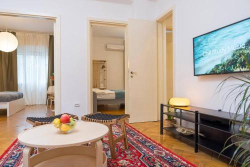 ein Wohnzimmer mit einem Tisch und einem TV an der Wand in der Unterkunft Ultra-central University Square Apartament Apartament in Bukarest