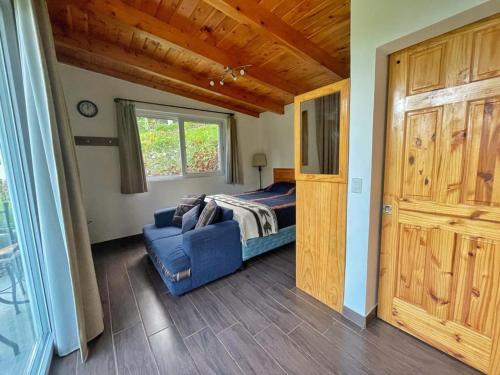a bedroom with a bed and a blue couch at Refugio del Volcan Casitas in San Pedro La Laguna