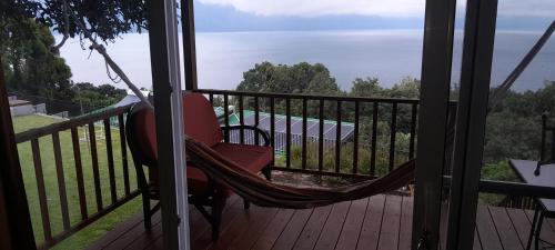 a hammock on a balcony with a view of the water at Refugio del Volcan Casitas in San Pedro La Laguna