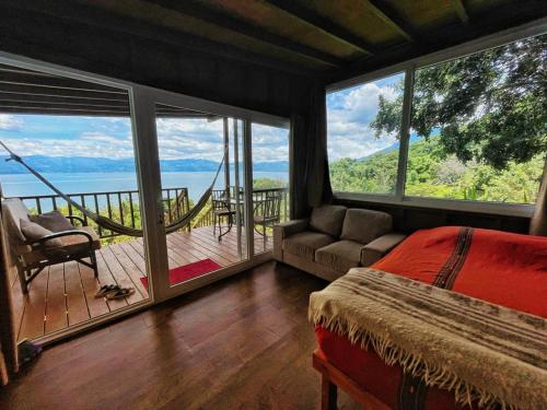a bedroom with a bed and a balcony with a view at Refugio del Volcan Casitas in San Pedro La Laguna