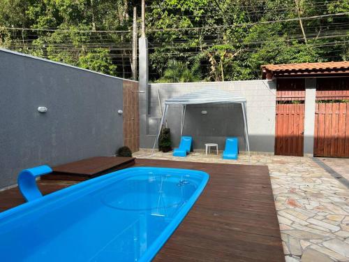una piscina azul en una terraza con sillas azules en Casa charmosa com piscina em rua tranquila en São Sebastião