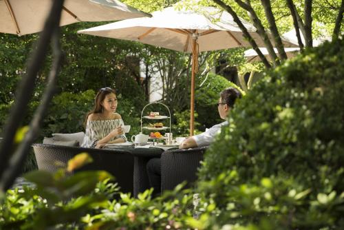 a man and woman sitting at a table under an umbrella at Four Seasons Hotel Hangzhou at West Lake in Hangzhou