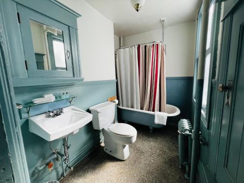 Baño azul con aseo y lavamanos en Arundel Mansions Hotel, en New Westminster