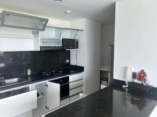 uma cozinha com armários brancos e bancadas pretas em Arriendo Apartamento Amoblado En Puerto Colombia Villa Campestre em Barranquilla