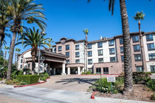 a hotel with palm trees in front of a building at Country Inn & Suites by Radisson, Ontario at Ontario Mills, CA in Ontario