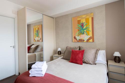 um quarto com uma cama branca e almofadas vermelhas em Sunshine Studio - GRU em Guarulhos