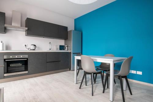 uma cozinha com uma mesa e cadeiras e uma parede azul em Alloggio moderno in centro paese em Corneliano d'Alba