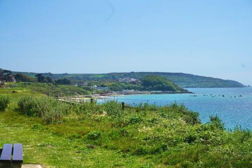 eine Bank auf einem Hügel mit Blick auf einen Wasserkörper in der Unterkunft CHINE COTTAGE self-catering coastal bungalow in rural West Wight in Freshwater