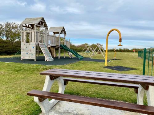 a park with a wooden bench and a playground at CHINE COTTAGE self-catering coastal bungalow in rural West Wight in Freshwater