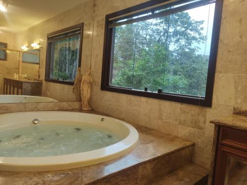 a large bathroom with a tub and a window at Vila da Sol Itaipava casas e estúdios in Itaipava