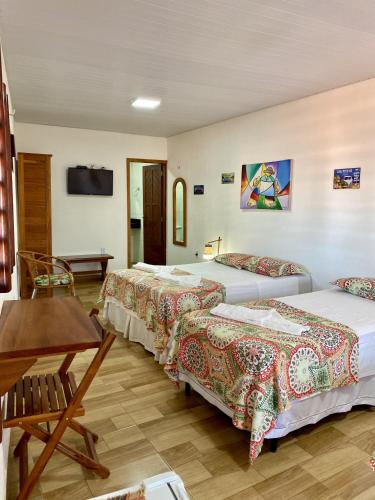 a hotel room with two beds and a table at Pousada São Pedro in Flecheiras