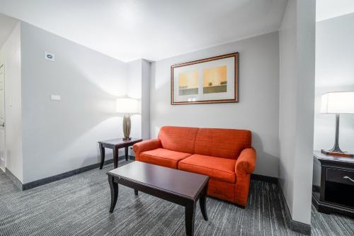 a living room with an orange couch and a table at Country Inn & Suites by Radisson, Ontario at Ontario Mills, CA in Ontario