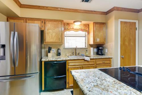 a kitchen with a stainless steel refrigerator and wooden cabinets at Expansive Texas City Retreat about 16 Mi to Galveston! in Texas City