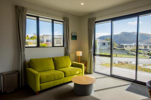 a living room with a green couch and large windows at Skyblue Tekapo in Lake Tekapo