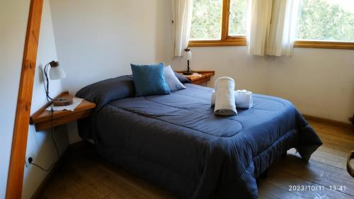 a bedroom with a bed with a blue blanket at ABROJITOS in Villa La Angostura