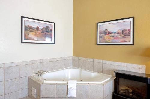 a bath tub in a bathroom with two pictures on the wall at Best Western Plus Guymon Hotel & Suites in Guymon