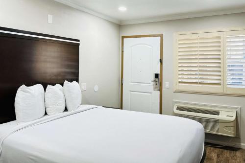ein weißes Bett in einem Zimmer mit Fenster in der Unterkunft Rodeway Inn Lemon Grove San Diego East in Lemon Grove