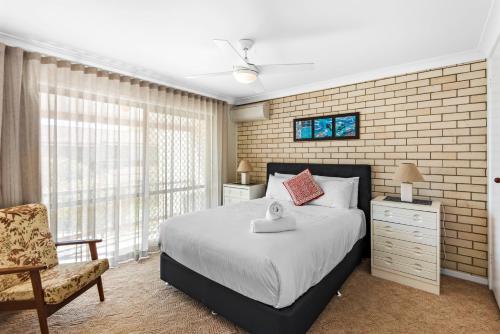 a bedroom with a bed and a chair and a window at Kenway Lodge in Ballina
