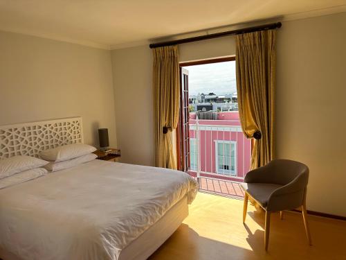 1 dormitorio con 1 cama, 1 silla y 1 ventana en De Waterkant Piazza Apartments, en Ciudad del Cabo
