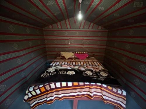 a small bedroom with a bed in a room with striped walls at Wadirum winter in Wadi Rum