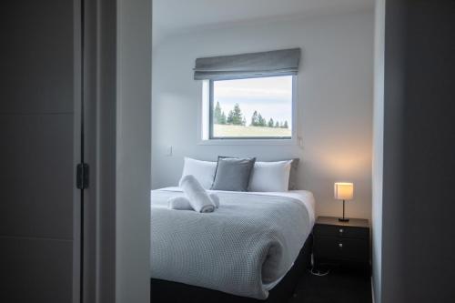 a bedroom with a white bed with a window at Skyrim Lodge in Lake Tekapo