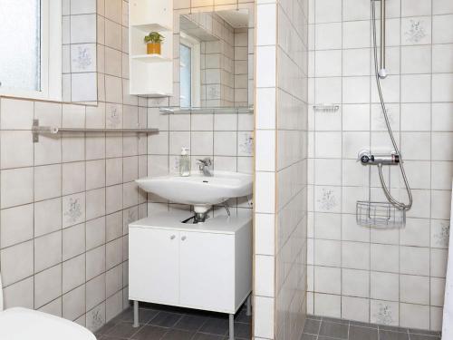 La salle de bains blanche est pourvue d'un lavabo et d'un miroir. dans l'établissement Holiday home Karby II, à Karby