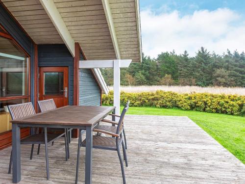 una mesa de madera y sillas en el porche de una casa en 6 person holiday home in ster Assels, en Sillerslev