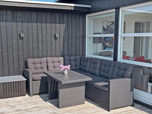 eine Terrasse mit einem Sofa, 2 Stühlen und einem Tisch in der Unterkunft 6 person holiday home in Slagelse in Slagelse
