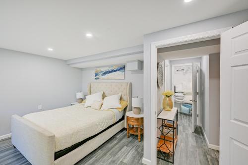 a white bedroom with a bed and a bathroom at New York Abode with Pool and Patio, Near Times Square! in Islip Terrace