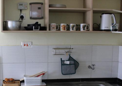 una cocina con fregadero y algunos vasos en un estante en SIMBA'S NOOK - A modern Budget Studio Apartment in Syokimau, Nairobi with Fast WiFi & Netflix - Near the JKIA Airport, SGR Station & Gateway Mall, en Syokimau