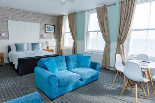 a living room with a blue couch and a bed at The Clarendon Hotel in Deal
