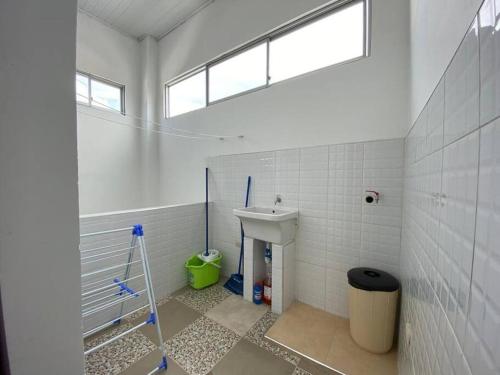 een witte badkamer met een wastafel en een raam bij D’Clau City Appartment in Iquitos