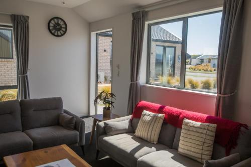 a living room with a couch and a table and windows at Skyrim Lodge in Lake Tekapo