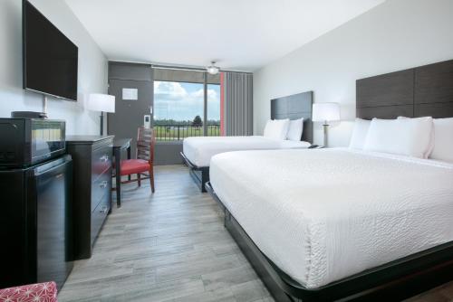 a hotel room with two beds and a flat screen tv at Ramada by Wyndham Gulfport I-10 Diamondhead in Diamondhead