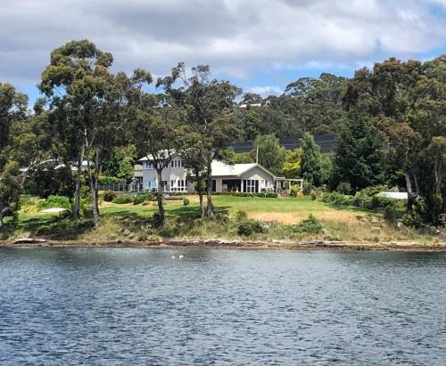 a house on an island in the water at Anchorage Waterfront Retreat in Castle Forbes Bay