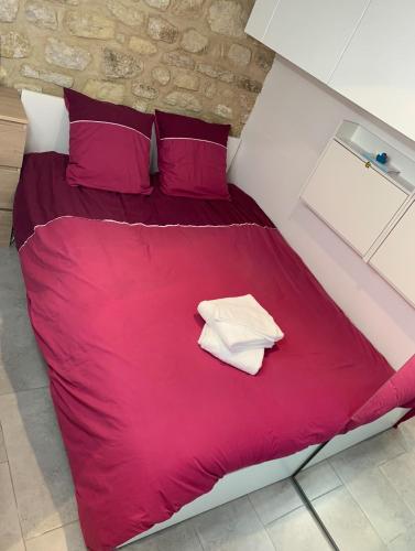 a red bed with red sheets and purple pillows at NEW Private apartment Paris city center - Les Arènes Pantheon Notre-Dame Jussieu Jardin des Plantes Quai de Seine in Paris