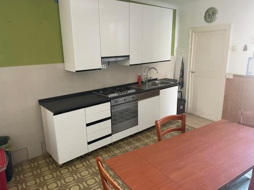 a kitchen with white cabinets and a table and a sink at Rovaio in Fivizzano
