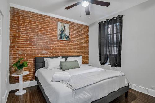 1 dormitorio con 1 cama grande y pared de ladrillo en HBG 1BR: Modern Vintage Gem, en Harrisburg