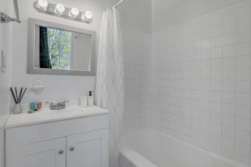 Baño blanco con bañera blanca y lavamanos en HBG 1BR: Modern Vintage Gem en Harrisburg
