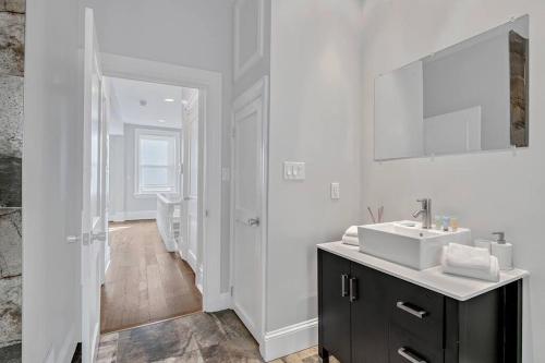 a white bathroom with a sink and a mirror at Charming HBG Haven: Cozy 1BR Apt in Harrisburg