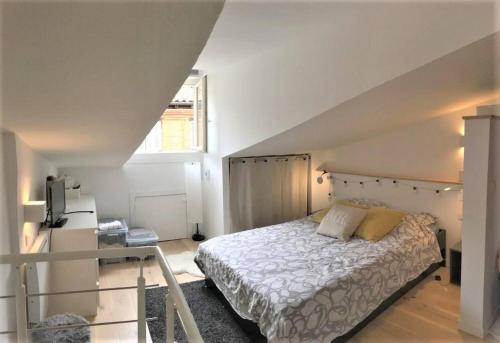 une chambre avec un lit blanc dans un grenier dans l'établissement Duplex aux Carmes, à Toulouse