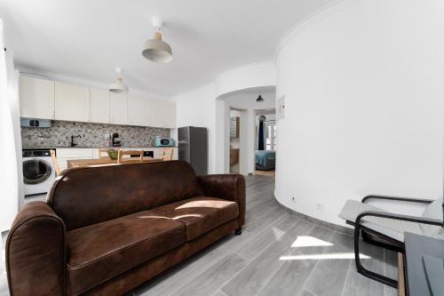 a living room with a brown couch and a kitchen at Pátio da Baixa in Setúbal