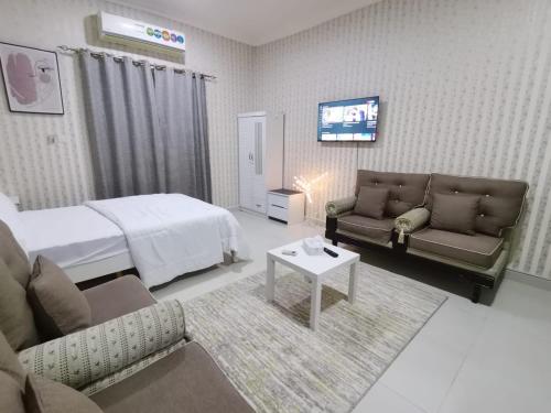 a bedroom with a bed and a couch and a tv at Studio in Ajman 