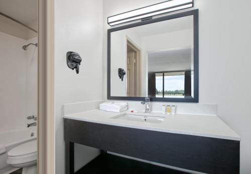 a bathroom with a sink and a mirror at Ramada by Wyndham Gulfport I-10 Diamondhead in Diamondhead