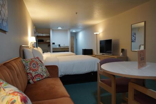 a hotel room with two beds and a couch and a table at Timberland Inn & Suites in Castle Rock