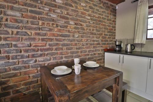 una mesa de madera en una cocina con una pared de ladrillo en Lion Den, en Marloth Park