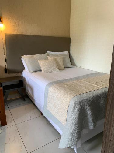 - une chambre dotée d'un grand lit avec des draps et des oreillers blancs dans l'établissement Saquarema Surf Apê, à Saquarema