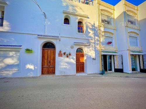 a white building with wooden doors on a street at Riad Al-Qurtubi in Tangier